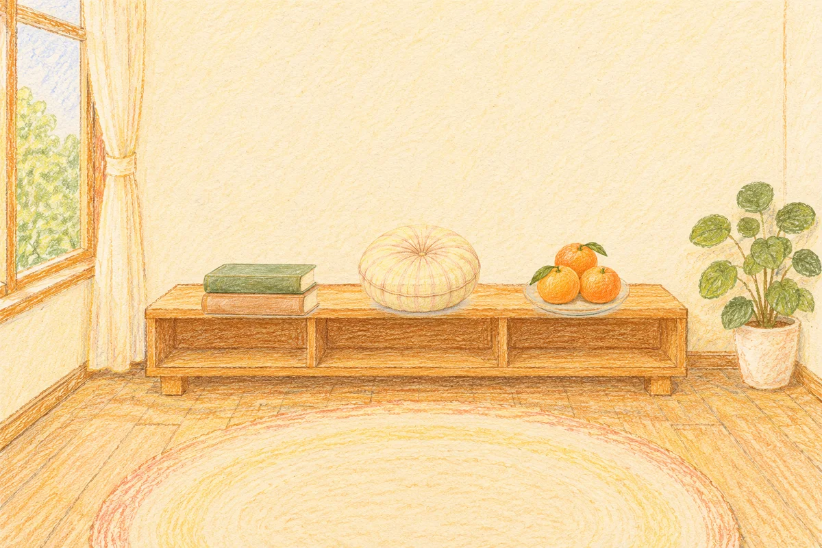 신천동 여성전용 얼굴 마사지 안내 그림, 낮의 창가 낮은 선반 위에 놓인 책 두 권, 둥근 쿠션, 귤이 담긴 접시